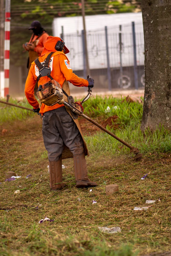 Man wearing protective gear using string trimmer outdoors.