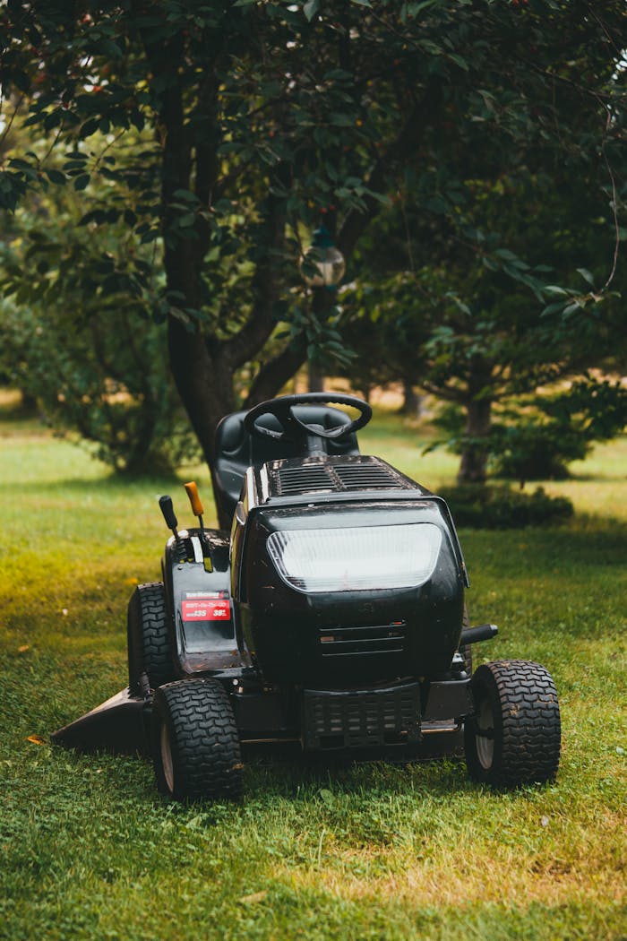 A riding lawn mower in a verdant backyard surrounded by trees, perfect for yard maintenance.
